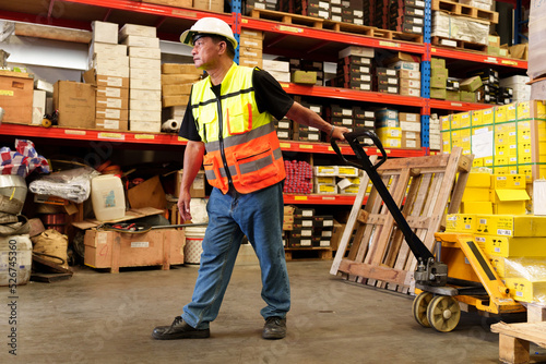 Worker is working hand pallet truck or pallet hand jack it goods product item on top of the pallet.