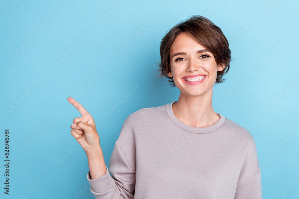 Portrait of lovely adorable woman bob hairstyle wear gray sweatshirt directing empty space sale banner isolated on blue color background Portrait of lovely adorable woman bob hairstyle wear gray sweatshirt directing empty space sale banner isolated on blue color background
