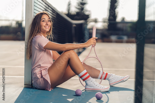 Chica joven con septum y conjunto de tenis rosa en cancha de tenis con raqueta photo