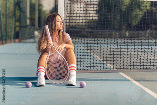 Chica joven con septum y conjunto de tenis rosa en cancha de tenis con raqueta photo