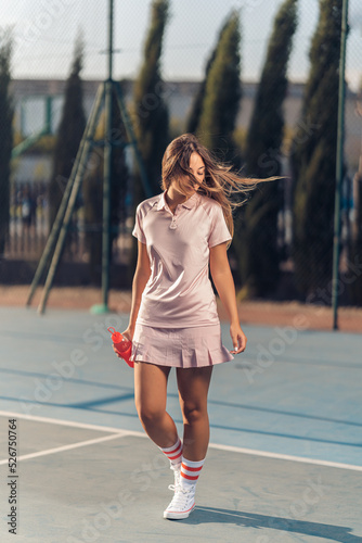 Chica joven con septum y conjunto de tenis rosa en cancha de tenis con raqueta