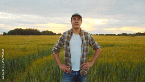 Farmer in front of a sunset agricultural landscape. Man in a countryside field. Country life, food production, farming and country lifestyle.
