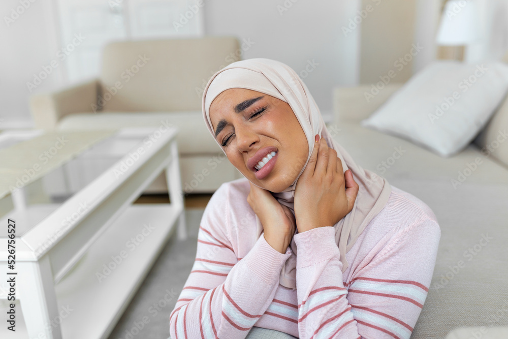 Unhappy young Arabic muslim woman with hijab suffering from pain in the neck Unhappy young Arabic muslim woman with hijab suffering from pain in the neck
