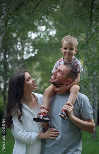 dad holds his son on shoulders , mom stands nearby. High quality photo