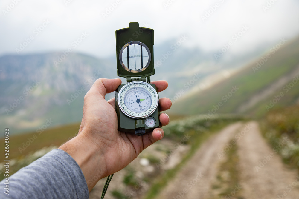 Hand with a compass on a mountain road Hand with a compass on a mountain road