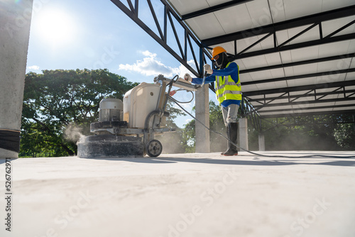 Construction worker using machine polishing surface floor smoothing and finishing hardener or epoxy concrete at construction site. Concrete floors.