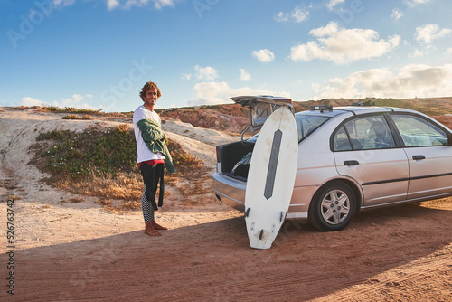 Photography Positive curly surfer smiling to the camera near his surfboard laying at the car