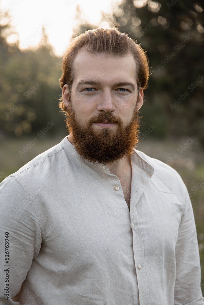 young man standing in beige clothes in the park and smiling looking at the camera young man standing in beige clothes in the park and smiling looking at the camera