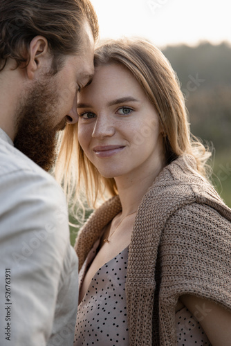 young woman hugging a man in the park and looking at the camera smiling