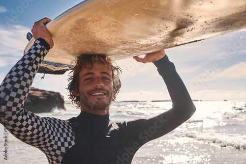 Surfer man athlete with wet hair holding surfboard at the head on summer beach