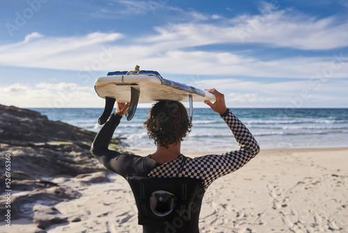 Male surfer holding board at the head and watching waves before the training