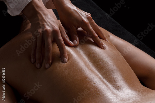 girl massage therapist makes a massage close-up on a dark background. close-up massage