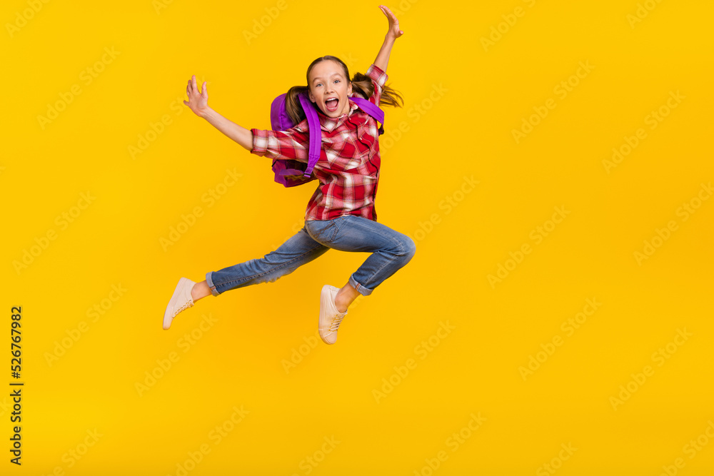 Photo of sweet impressed schoolkid dressed plaid shirt jumping high running fast empty space isolated yellow color background Photo of sweet impressed schoolkid dressed plaid shirt jumping high running fast empty space isolated yellow color background