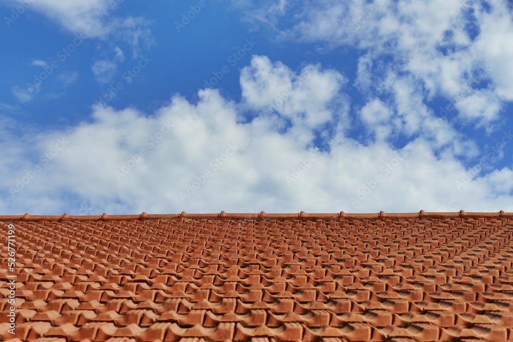 perspective view of a tiled roof under a blue cloudy sky