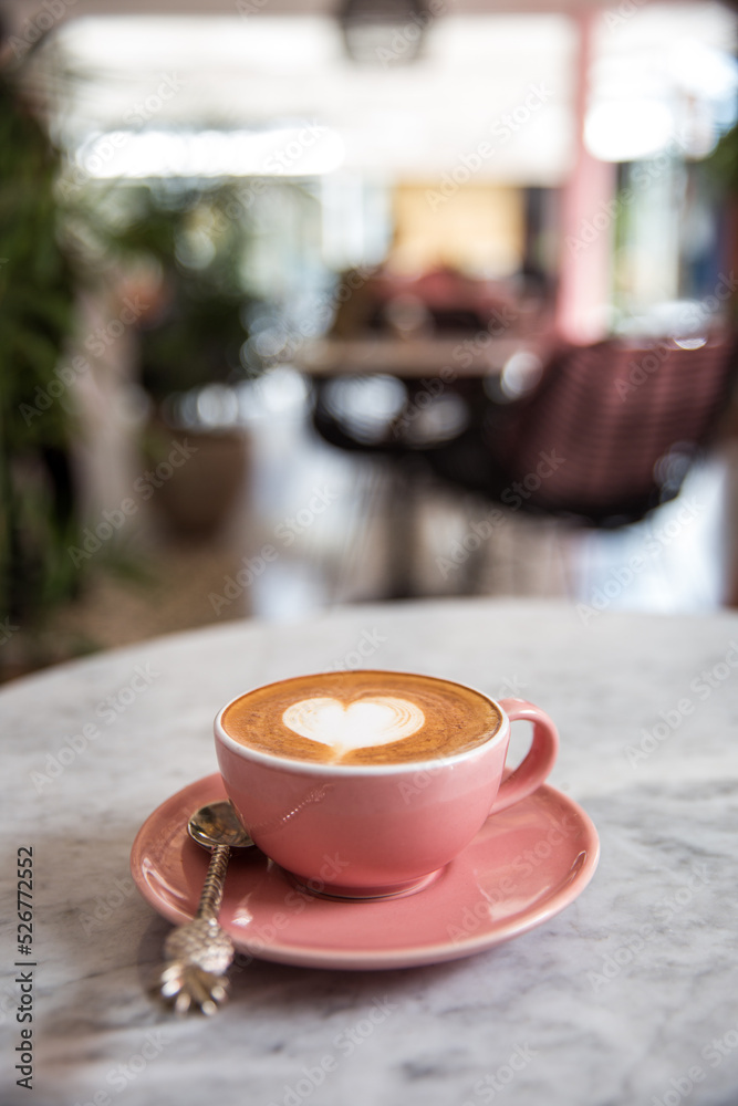 Pink cup of cappuccino with beautiful latte art on marble table background.
