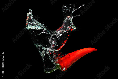 Hot chilli pepper splashing in water on black