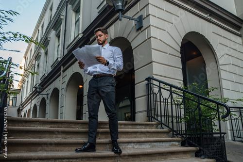 Shot of businessperson dressed in formal attire analyzing documents outdoors in fresh air.
