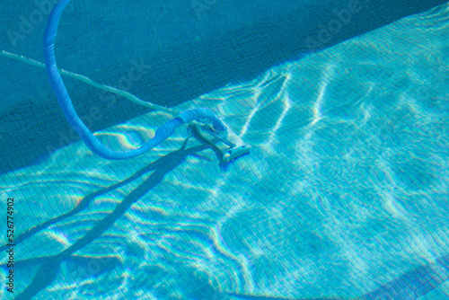 A manual pool cleaner under the waters of the blue tile pool. Pool cleaning and maintenance. photo