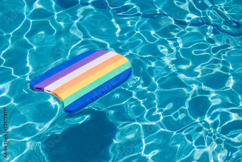 An isolated pool float of colorful lines floating on a sunny day in a tiled pool filled with water. Summer and vacations.