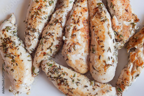 Overhead view of delicious and tender rosemary chicken tenderloins on a white plate. Easy recipes and healthy food.