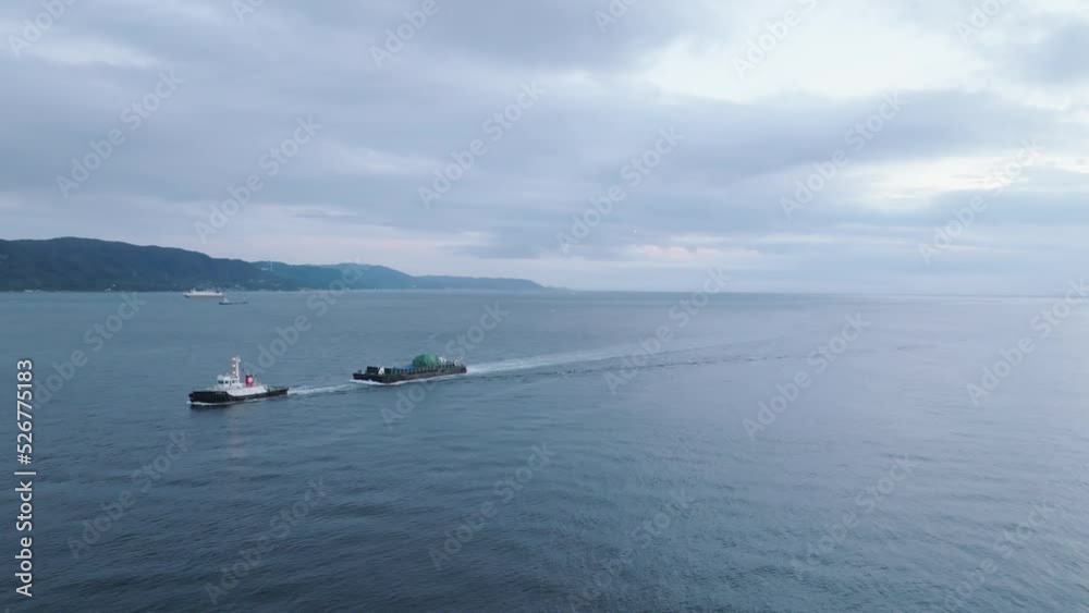 Small boat pulls cargo barge off coast at dusk Small boat pulls cargo barge off coast at dusk