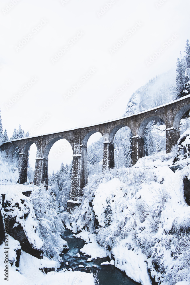 Fototapeta Mountain landscape with Sainte Marie bridge covered with snow in Les Houches, Chamonix valley, Eastern France. Viaduct bridge built to carry a railway over water.