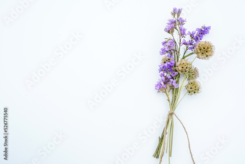 Fototapeta Naklejka Na Ścianę i Meble -  Bouquet of starflower seed pods and purple statice flowers tied with a twine bow. White background. Space for text.