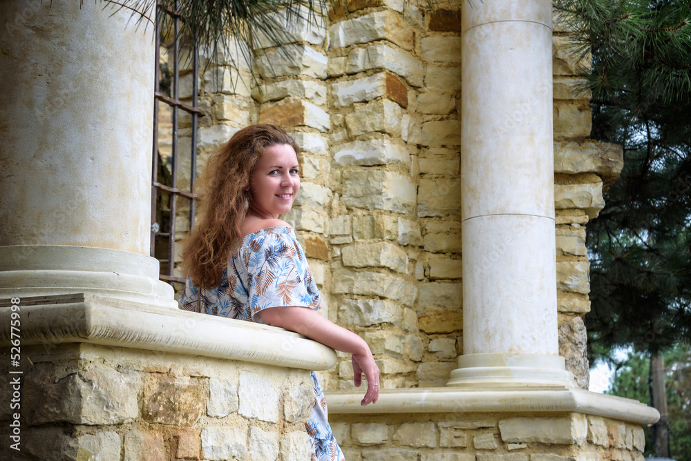 Portrait of young pretty woman on stairs near ancient historical building from stone and seashells