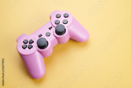 Pink video game controller, joystick for game console isolated on yellow background. Gamer control device close-up