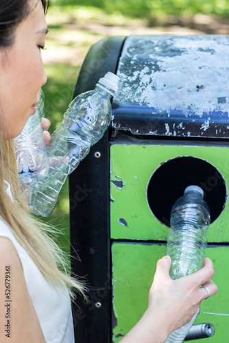 Vertical close-up shot of Asian woman throwing plastic bottle in recycling bin to care for the planet, eco-friendly gesture and the importance of recycling on this earth day
