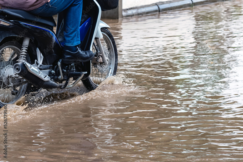 Foto de Man ride motorcycle passing through flooded road. Riding