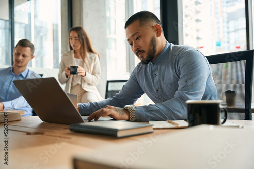Close up photo of young concentrated man working on laptop
