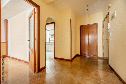 Entrance hall of a house with cherry wood door  herringbone oak parquet flooring  access to multiple rooms  fitted wardrobes and cream yellow painted walls