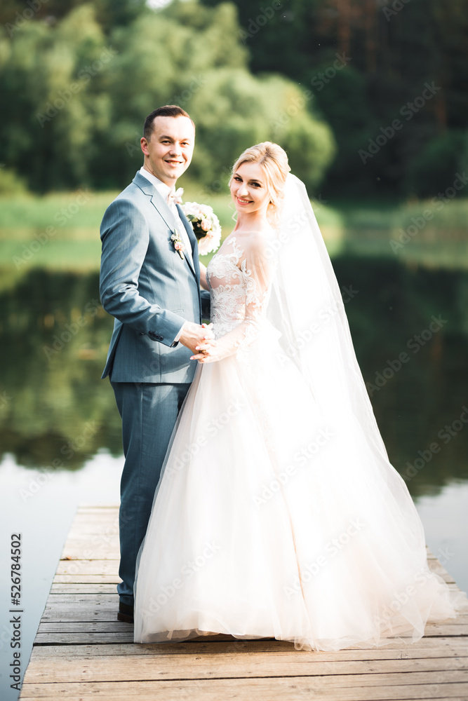 Beautiful bride and groom embracing and kissing on their wedding day outdoors Beautiful bride and groom embracing and kissing on their wedding day outdoors