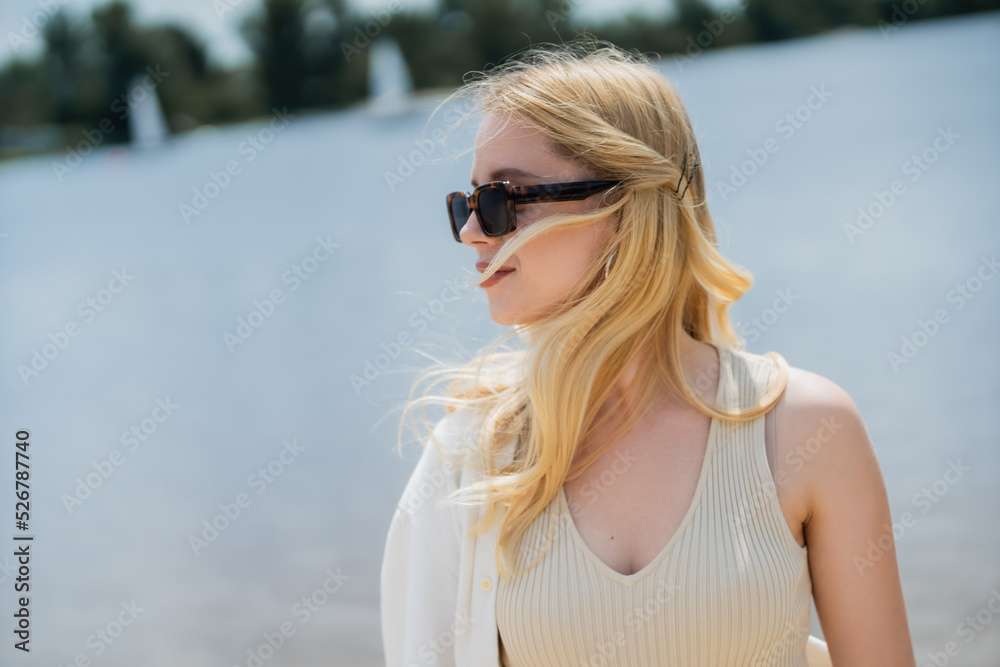 young blonde woman in fashionable sunglasses looking away outdoors. young blonde woman in fashionable sunglasses looking away outdoors.