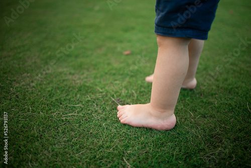 Boy feet in nature. bare feet in the green grass. little Happy child running at sunset barefoot outdoor. Concept of happy childhood