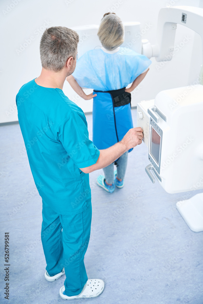 Obraz premium Doctor performing knee x-ray procedure on caucasian female patient