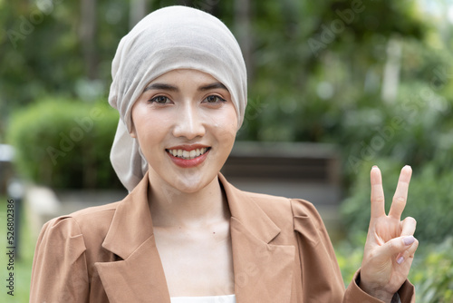 фотографія Hopeful rehabilitating Asian woman cancer patient showing V for victory, winning