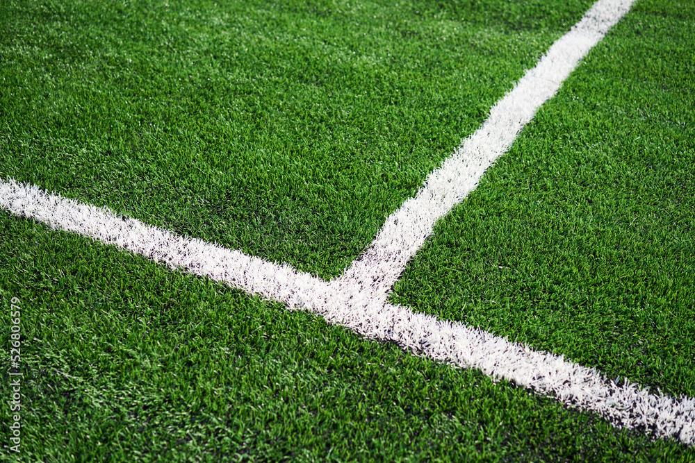Green synthetic grass sports field with white line.