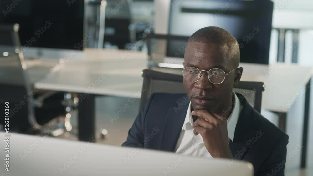 African-american attractive businessman in suit working on laptop in office, happy black ceo looking at computer screen thinks and analyzes looking at the computer screen, browsing web, using software African-american attractive businessman in suit working on laptop in office, happy black ceo looking at computer screen thinks and analyzes looking at the computer screen, browsing web, using software