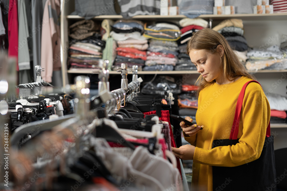 Positive woman choosing new clothes from rack in shop, young woman buyer shoppyng on clothes sale. shopping apparel fashion Positive woman choosing new clothes from rack in shop, young woman buyer shoppyng on clothes sale. shopping apparel fashion