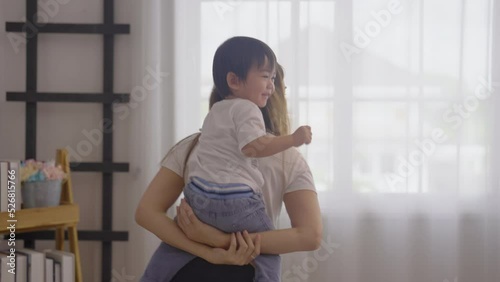 Asian mother hold and play with little son by ride on the back or piggyback in bedroom and they look happy and enjoy together to stay at home.