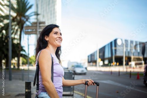 Happy woman with luggage outdoors in city