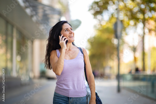 Smiling woman talking on mobile phone in city © mimagephotos