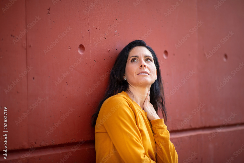 Thoughtful woman looking up while leaning against wall Thoughtful woman looking up while leaning against wall