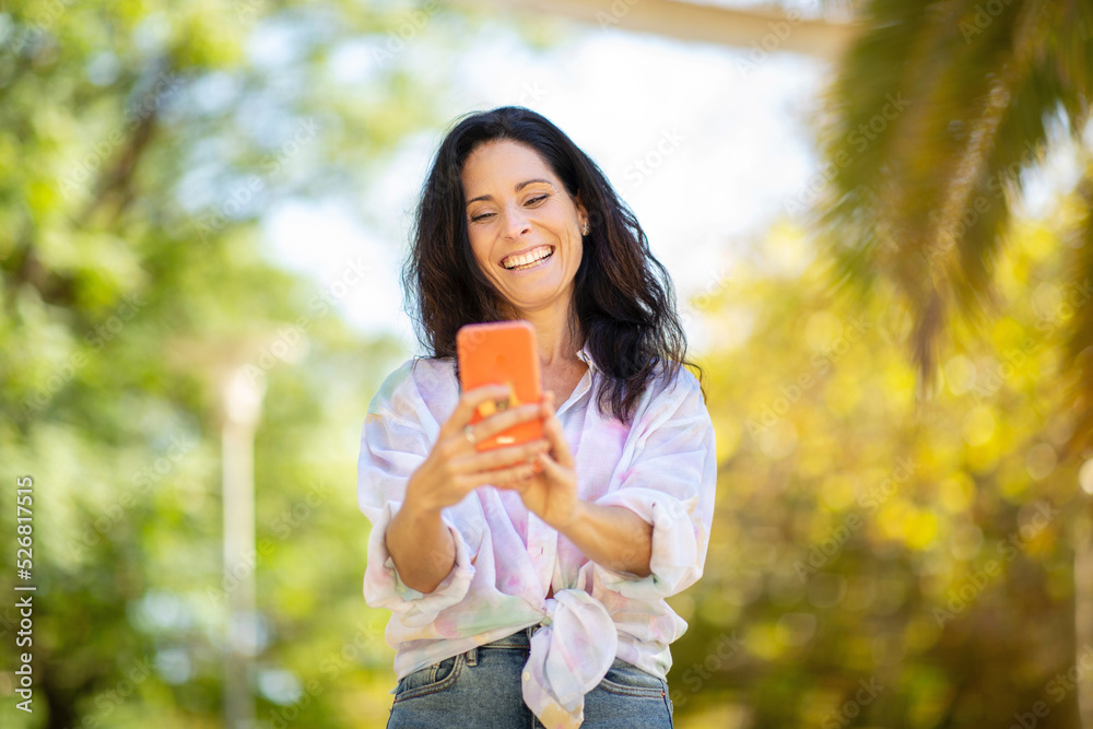 Cheerful woman using mobile phone at park Cheerful woman using mobile phone at park