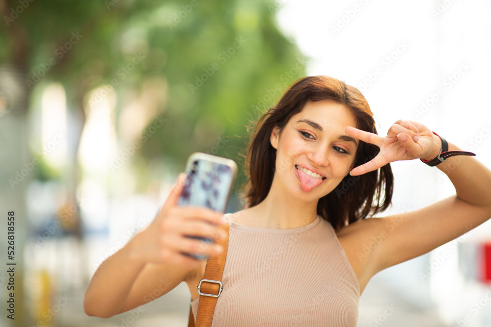Woman taking selfie outdoors with peace hand sign Woman taking selfie outdoors with peace hand sign