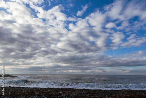Northern seascape with surf. Blue sky with clouds.