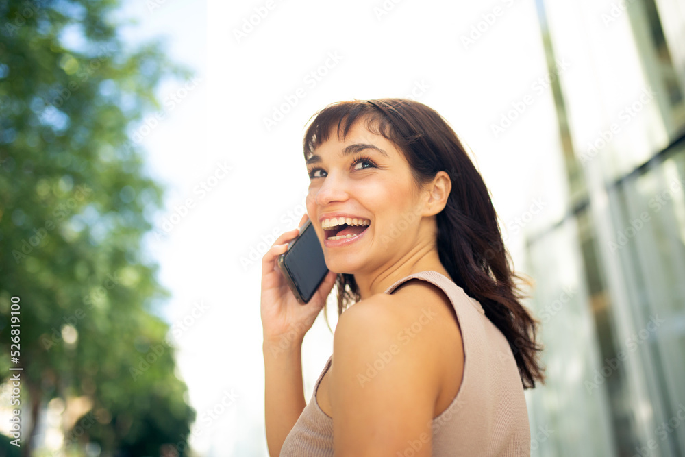 Cheerful young woman talking on cellphone in city Cheerful young woman talking on cellphone in city