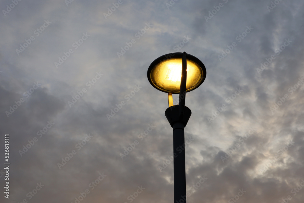 Glowing led lamp on background of evening sky with dark clouds. Electric lighting, energy-saving street lantern Glowing led lamp on background of evening sky with dark clouds. Electric lighting, energy-saving street lantern